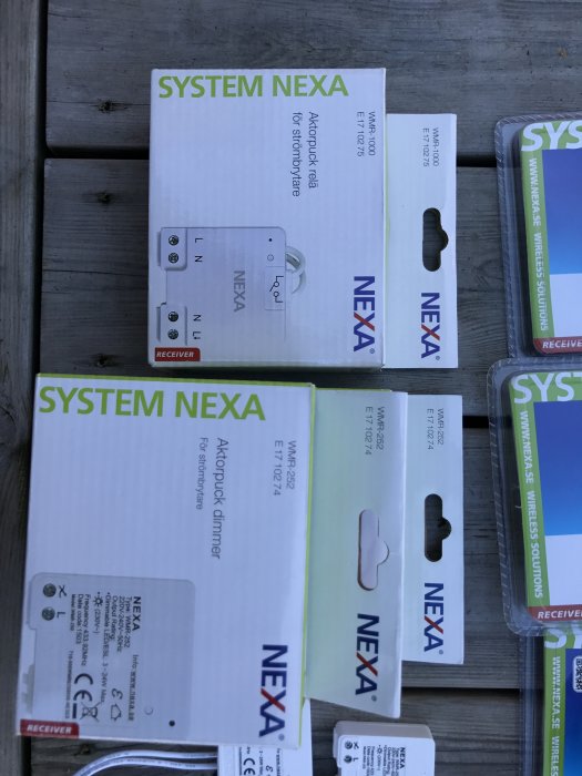 Nexa-systemförpackningar för trådlös strömbrytare och dimmer på träyta.