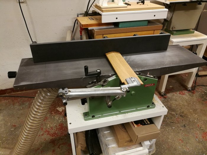 Hemmagjord anhåll monterad på en träbearbetningsmaskin i en verkstad, med synliga stålbeslag och handtag.