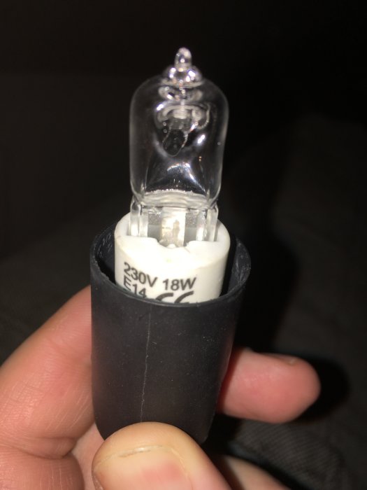 Större stiftlampa hålls i hand, märkt med "230V 18W E14", jämförs med mindre G4-lampa.