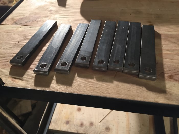 Metallbeslag för bygge av drinkvagn som ligger på ett träbord.