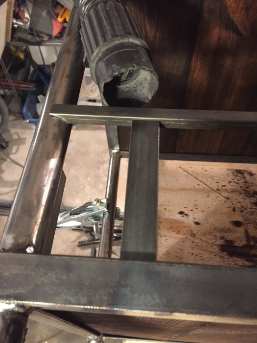 Del av en handbyggd drinkvagn i metall under konstruktion, detalj av hjul och ram.