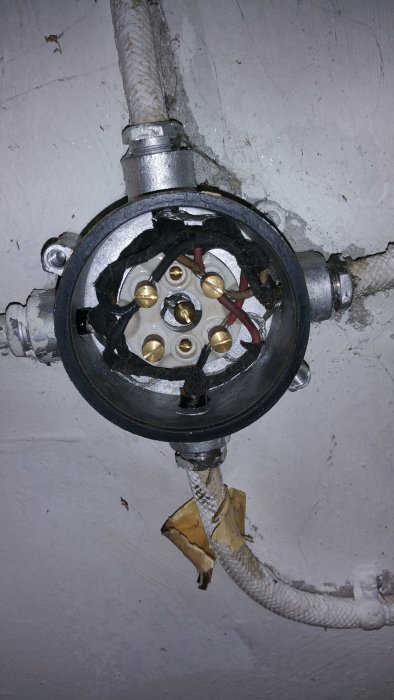 Öppnad kopplingsdosa med synlig mantlad kabel och flera anslutna ledare i ett garage.