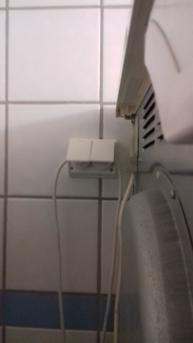 Eluttag på vägg i badrum ovanför kant på tvättställ, möjlig säkerhetsrisk.