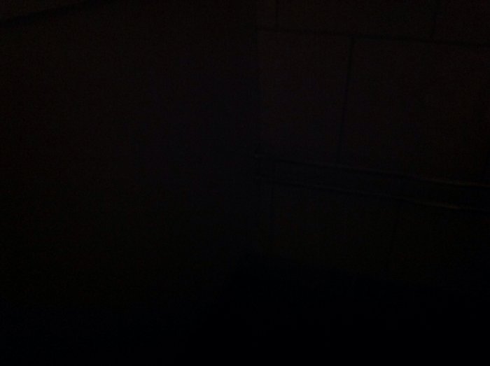 Mörk och nästan osynlig bild av ett badrum med svagt urskiljbara kakelväggar.
