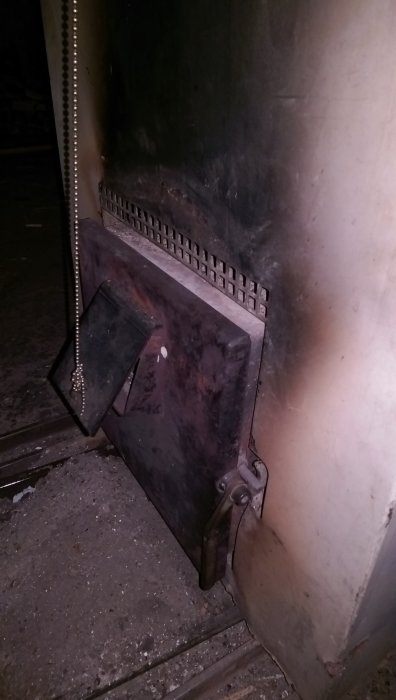 Gammal plåtpanna med stängd lucka, otillgänglig för öppning, belyst i en mörk miljö.