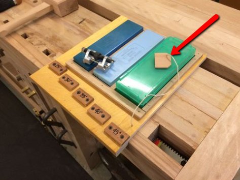 En trästruktur med en grön batteripack och flera mindre träblock markerade med röd pil.