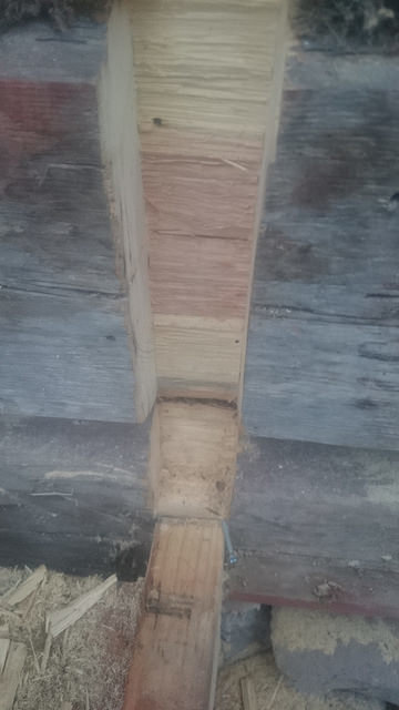 Detaljbild på tätning mellan träreglar i gammalt timmerhus, med synliga drevade och fyllda skarvar.
