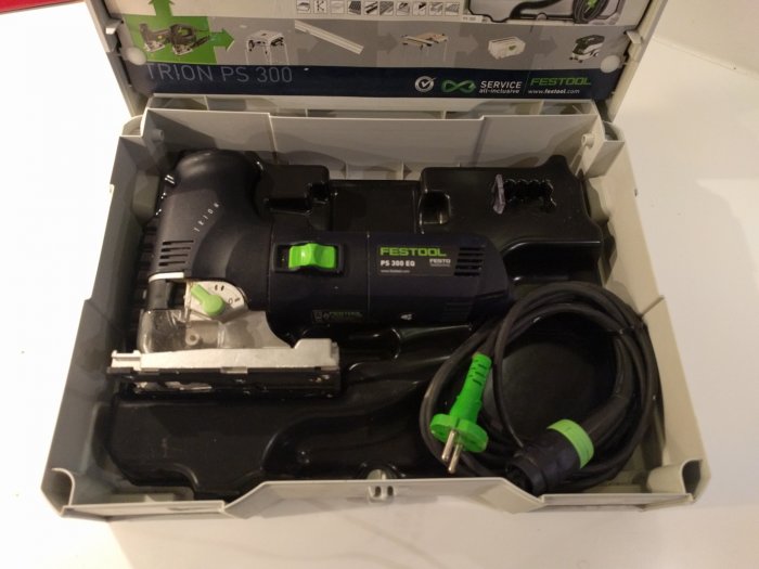 Festool sticksåg i öppnad låda med tillbehör och strömkabel, redo att komplettera svartgröna verktygssamlingen.