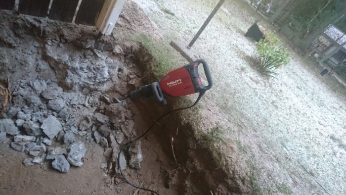 En Hilti TE 1000 AVR rivningshammare på ett grusigt och grävt område med sprängda betongbitar.