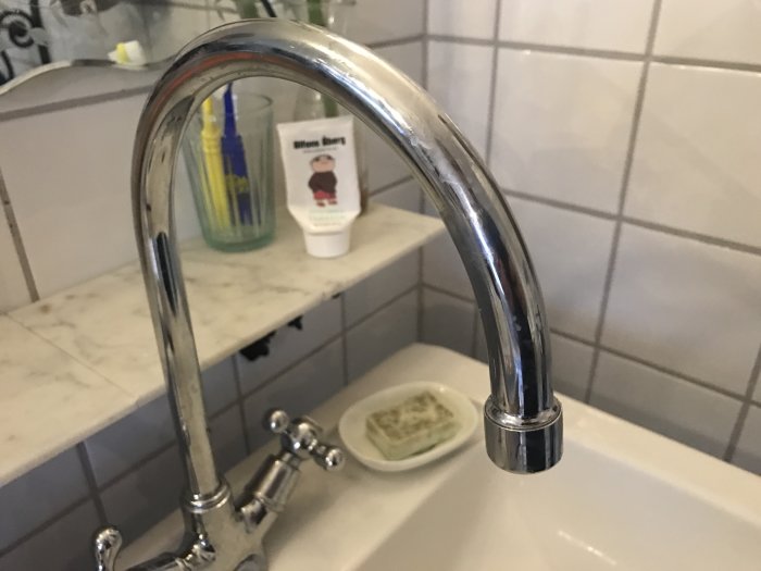 Kromad tvättställsblandare med skadad strålsamlare i ett badrum.