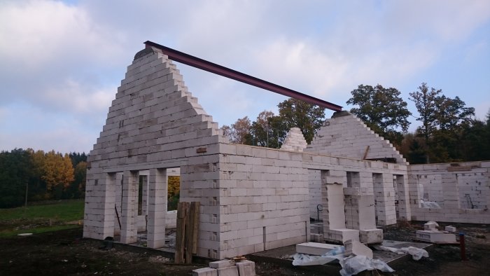 Konstruktion av ett hus med oavslutade betonggavlar och en monterad järnbalk.