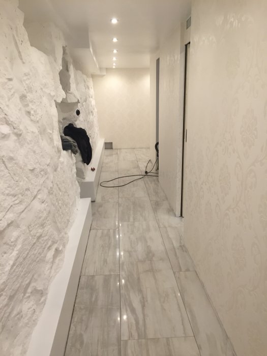 Renoverad källarkorridor med vitmålad naturstensgrund, glänsande golv och tapetserade väggar.