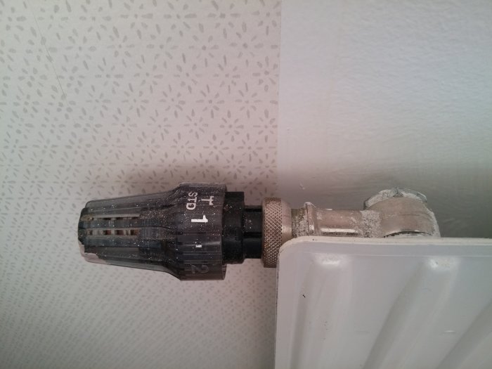 Termostatventil på ett kallt radiatorselement med synliga rörkopplingar.