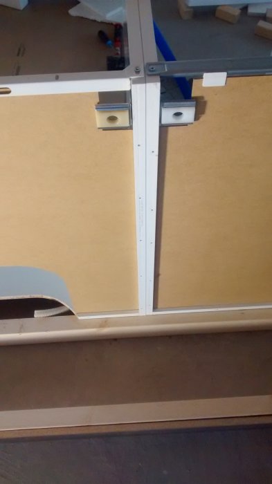 Eldragning i köksrenovering visar en öppen metallram med kablar och utstick av rör för elanslutningar på en träyta.