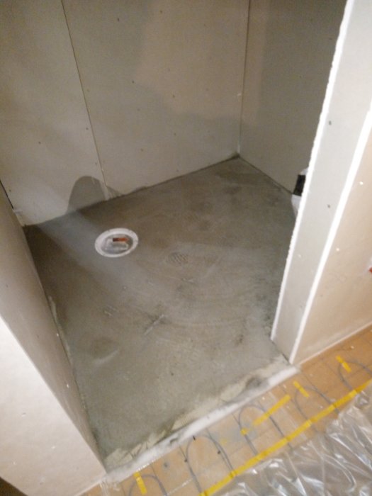 Flytspacklat golv med avstängningslist runt golvbrunn vid byggprojekt.