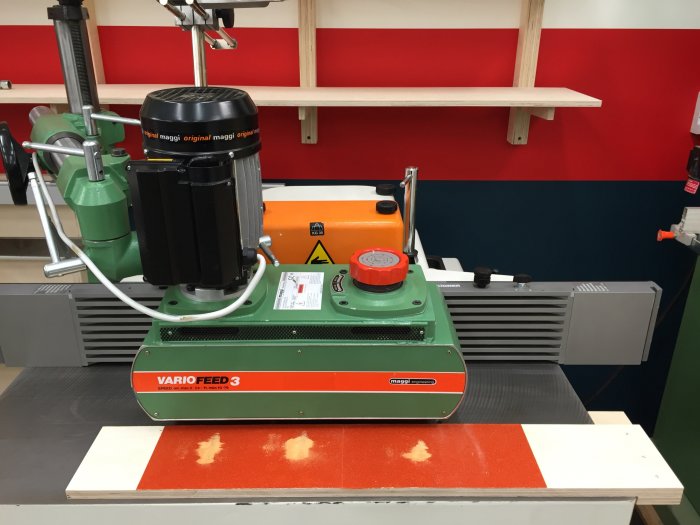 Reparerat matarverk VARIO-FEED 3 på arbetsbänk med plywood, limrester och sandpapper synliga.