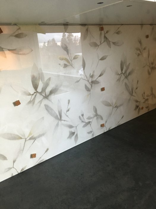 Delvis oavslutad renovering visar vägg med blommönstrad tapet och oskyddad gips i taket.