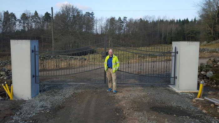 Person i reflexväst står framför nyinstallerade, eldrivna grindar med armeringsdetaljer och förstärkta formar.