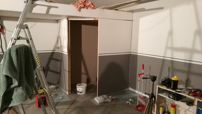 Toavägg under renovering, målad utvändigt, verktyg och stege syns.