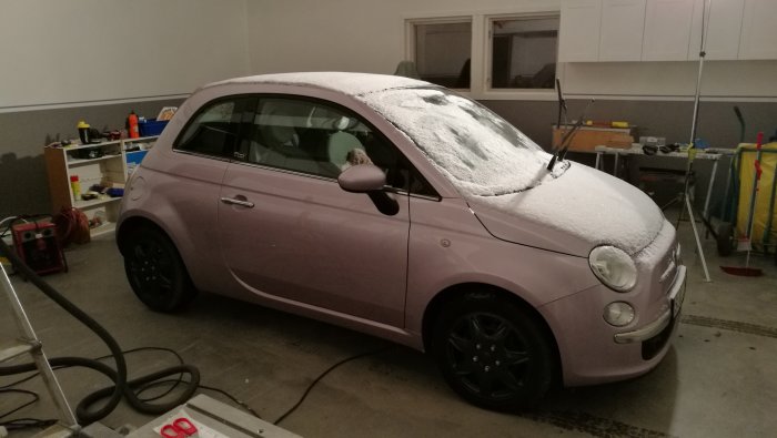 Ny målad garagevägg med hängande väggskåp och en snötäckt ljuslila bil framför.