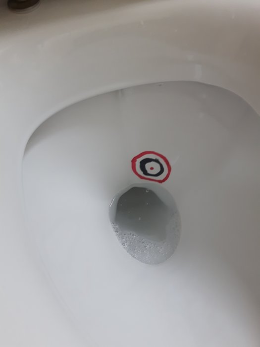 Måltavla målad med nagellack i en ren toalettstol för att minska stänk.