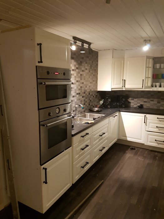 Köksrenovering påbörjad med borttagna överskåp och omplacerad vitvaror såsom kyl/frys och ugn.