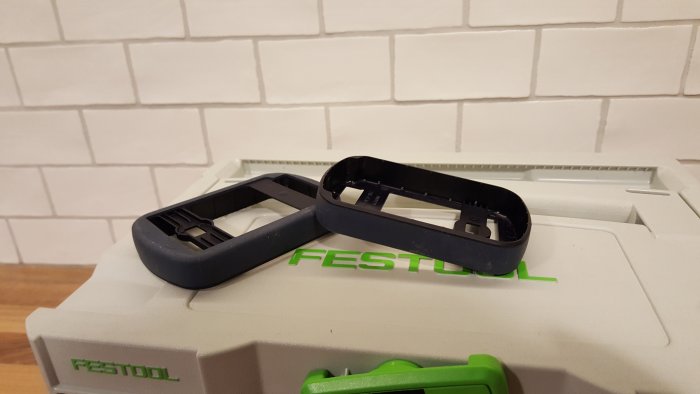 Två tomma plasthöljen med Festool-logotyp, troligtvis batterifack, på en verktygslåda.