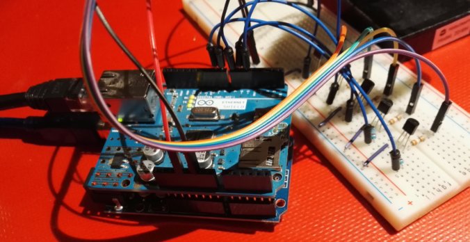 Arduino-kort kopplat till breadboard med sladdar och komponenter på röd bakgrund.