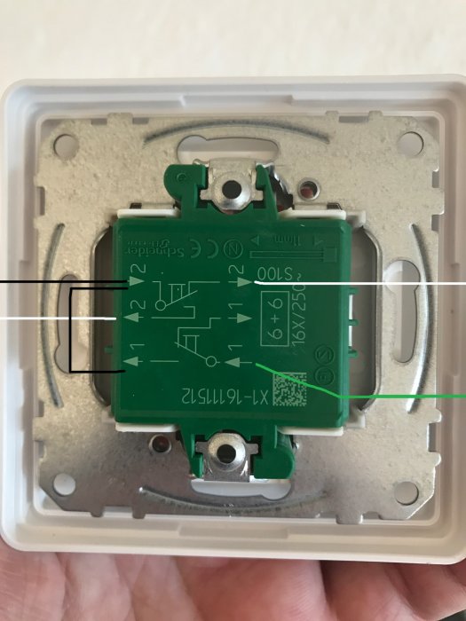 En hand håller en öppen elektrisk strömbrytare med synliga kretskort och kabelanslutningar.