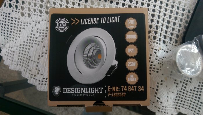 Förpackning av en 3000K LED-lampa, Designlight, med information om 590 lumen och 230V på ett bord.