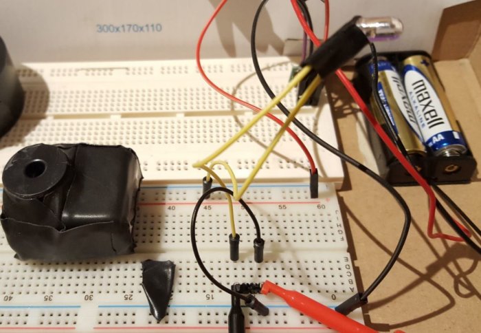 Breadboard med elektroniska komponenter, transformator, batterihållare med AA batterier och kabelanslutningar.