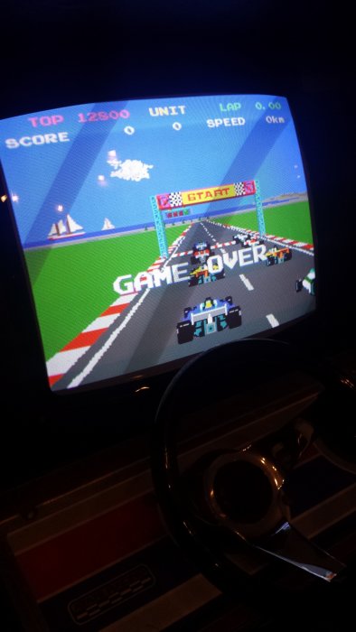 Återställt Atari Pole Position arkadspel med skärmbild av 'GAME OVER' och en ratt i förgrunden.