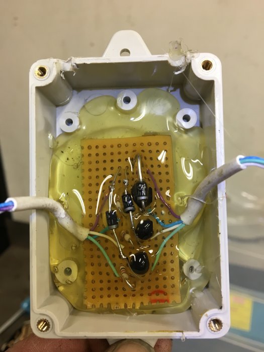 Hembricolage av en elektronisk krets med dioder och kabelanslutningar i en öppen dosa.