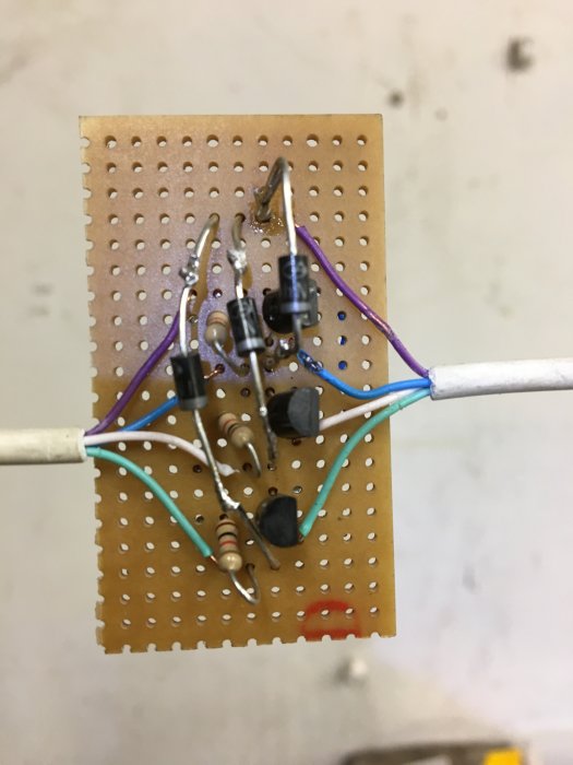 DIY-elektronikprojekt på kretskort med lödda komponenter och färgade ledningar.