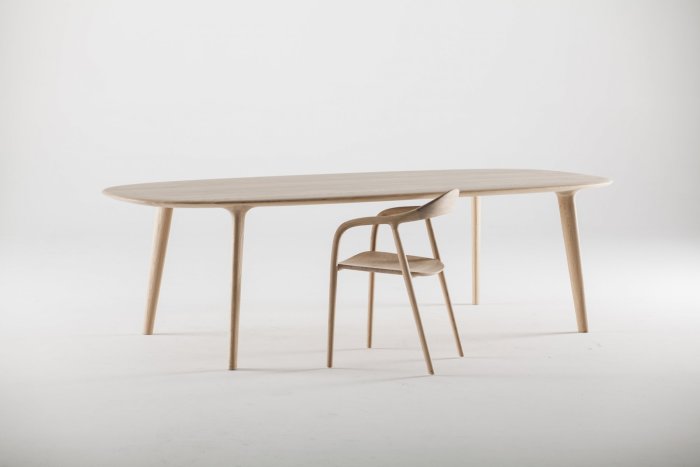 Modern träbord med tjock skiva och svängda ben, ackompanjerat av en matchande stol.