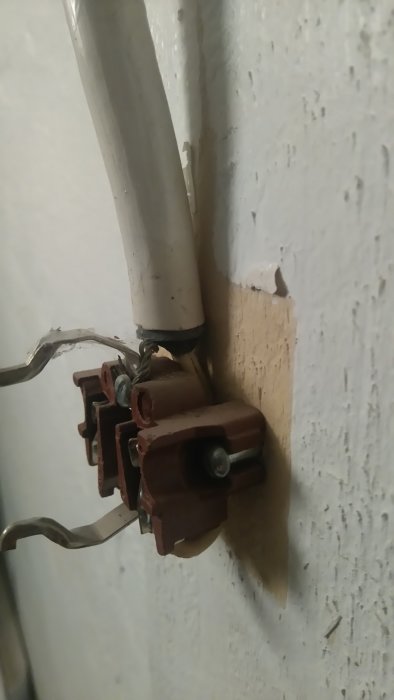 Närbild på ett öppnat eluttag i källarvägg med synlig oskyddad jordkabel utan gulgrönt hölje.