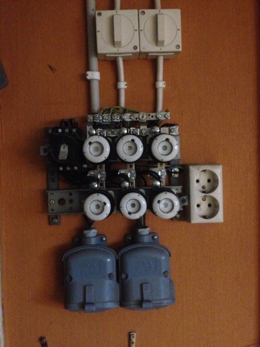 Äldre elcentral med flera säkringar, kablar och uttag inklusive 380V uttag och väggkontakter, utan jordfelsbrytare.