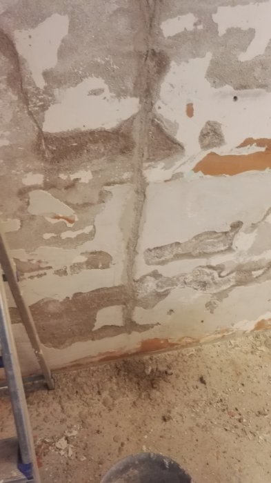 En grundmur med spacklade sprickor, där ett element nyligen blivit borttaget, redo för reparation.