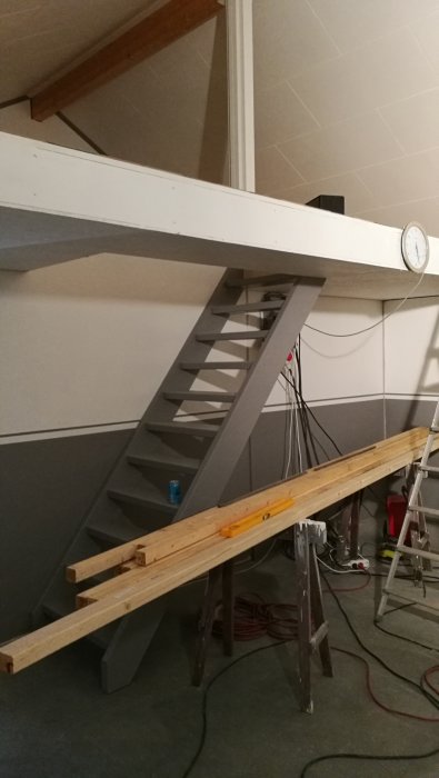 Nyinstallerad trätrappa och en påbörjad arbetsbänk i ett renoveringsprojekt.