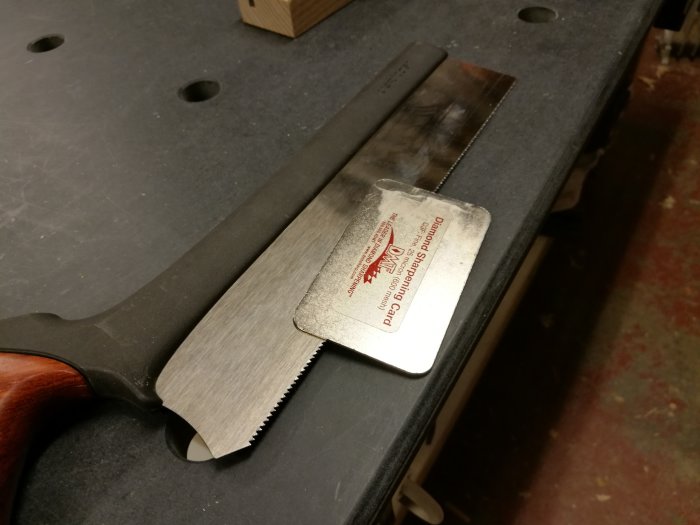 Handsåg med nyligen filade tänder vilar på en arbetsbänk, redo för mer finjustering i renoveringsprojektet.