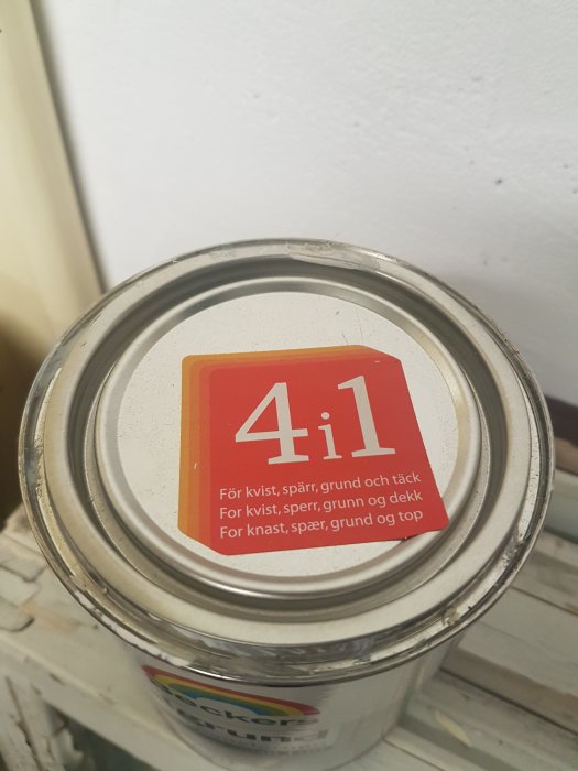 Stängd burk med grunderingsfärg märkt med '4 i 1' för diverse underlag, placerad på en otydlig yta.