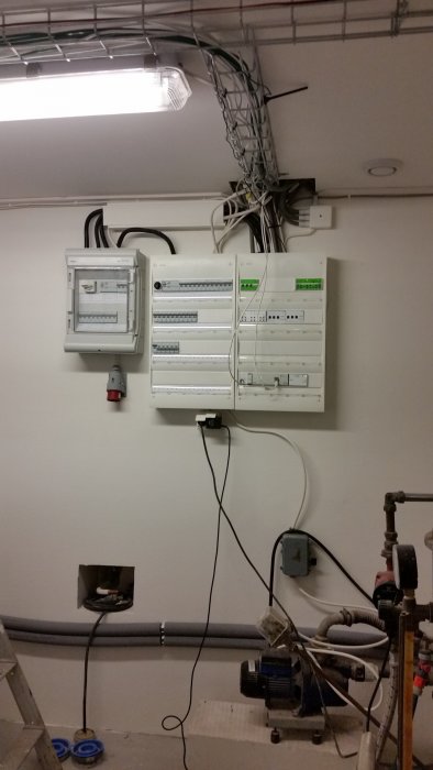 Elektriskt skåp med KNX-system installerat på vägg och kablar, samt arbetsbelysning i taket.