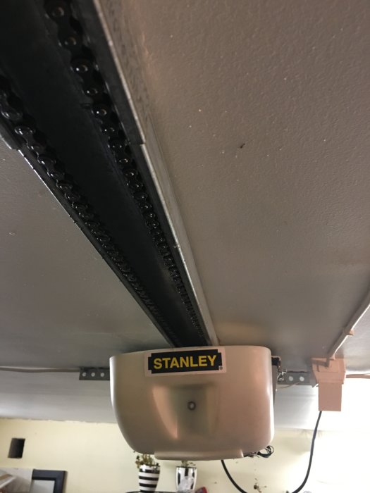 Garageportsöppnare av märket Stanley monterad under tak med synlig kedjedrift.