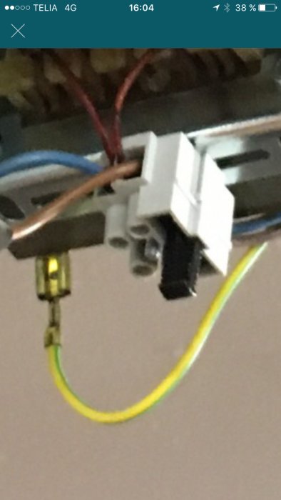 Elektrisk installation med två säkringar, en med grön diod som lyser, och kablar i bakgrunden.