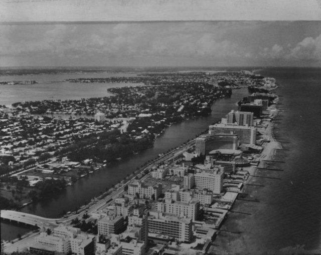 Svartvit flygbild över Miami från 1960 med byggnader längs vattnet och ett utvecklat vägnät.