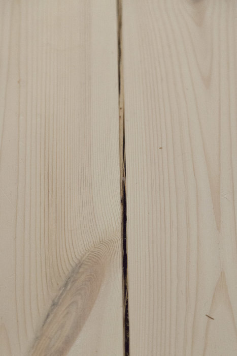 En detaljbild av ljusa trägolvplankor med en markant skarv och glipa mellan dem.