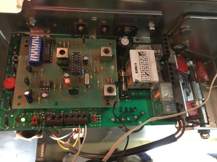 Öppet elektronikskåp med kretskort och säkringar synliga, indikerar en bytesprocess av säkringar.