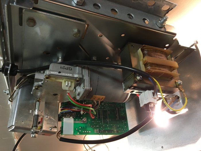 Elektrisk apparat öppen med synligt relä, säkringar och kretskort, med brummande ljudproblem.