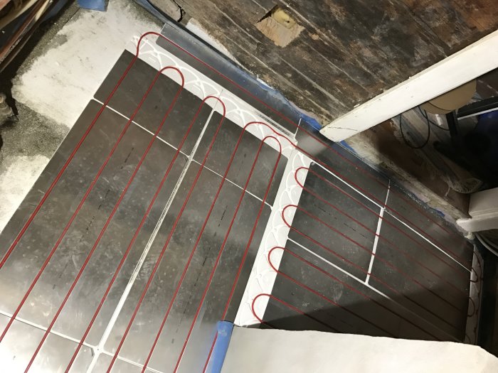 Uppifrån-bild på T2 Reflecta isoleringsplattor med T2 Röd värmekabel installerad på ett golv.