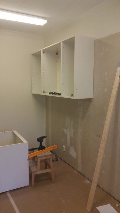 Renovering av kök med upphängt IKEA-överskåp och början av köksmontering med verktyg synliga.